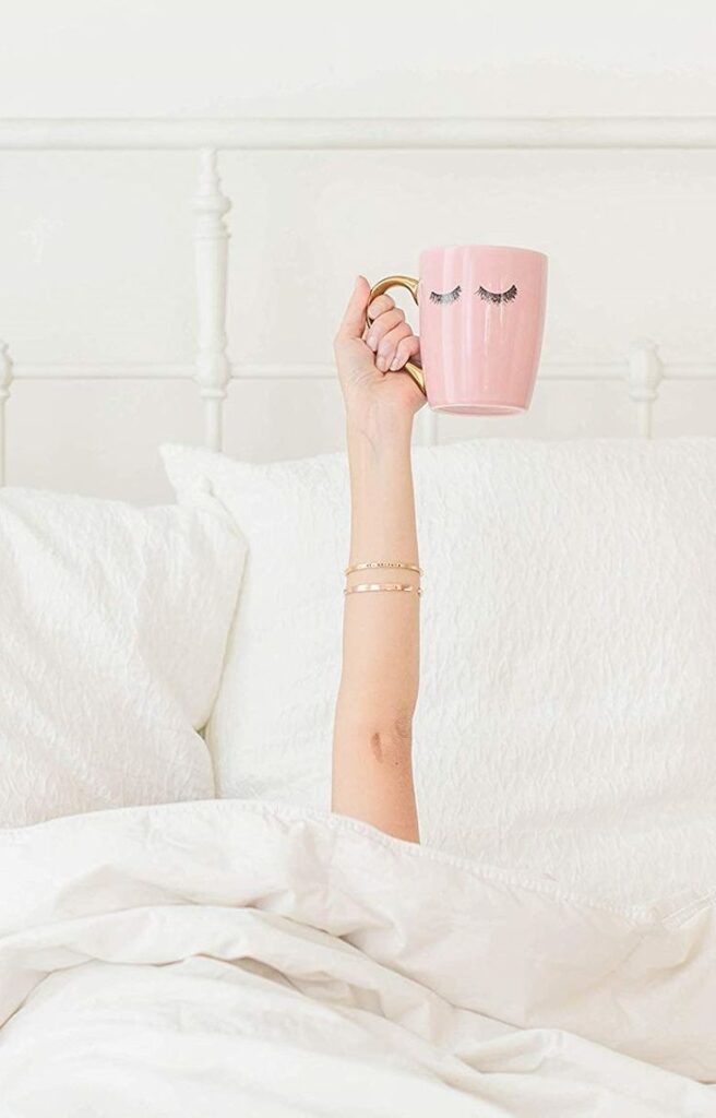 Kubek gorącej, różowej kawy z mlekiem w łóżku