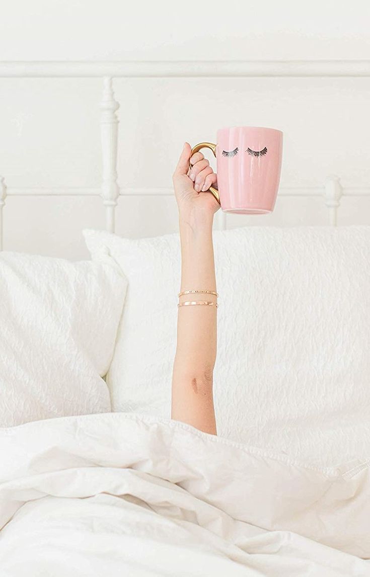 Kubek gorącej, różowej kawy z mlekiem w łóżku